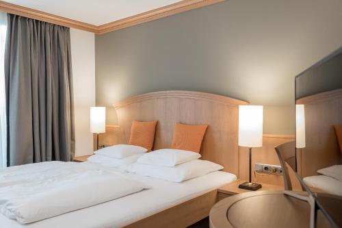a bedroom with a large white bed with two lamps at Hotel Tyrolerhof in Sölden