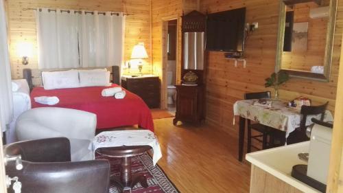 1 dormitorio con cama roja y mesa en Villa Billy, en Gan Ner