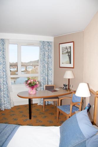 a hotel room with a desk and a table at Mercure Nevers Pont De Loire in Nevers