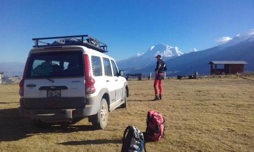 a man standing next to a white van in a field at Hostal Casa del Montañista in Huaraz