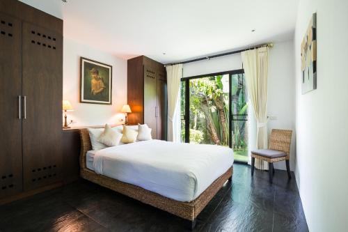 a bedroom with a bed and a large window at Baan Thai Surin Garden in Surin Beach