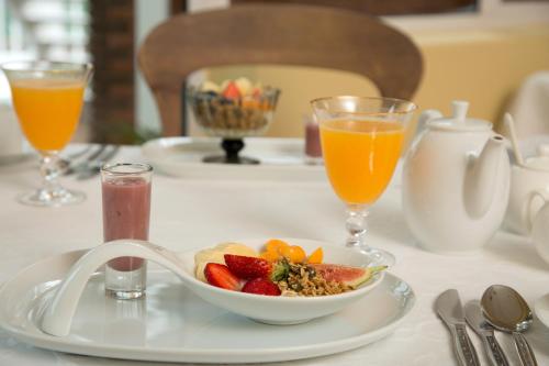 a table with a bowl of fruit and two glasses of orange juice at Serendipity Country House & Restaurant in Wilderness