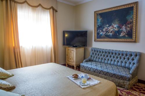 a room with a bed and a couch and a television at Villa Tuscolana in Frascati