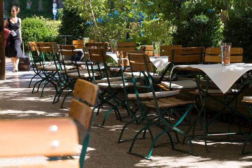 a row of tables and chairs with a woman walking by at Bio-Hotel Alter Wirt in Grünwald