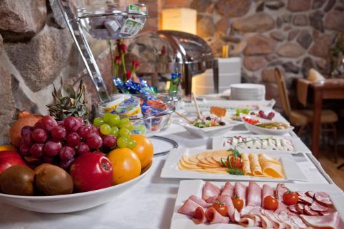 a table topped with plates of food and fruit at Hotel Masovia in Giżycko