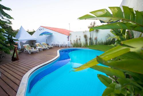 una piscina en un patio trasero con terraza de madera en Pousada dos Quatro Cantos en Olinda