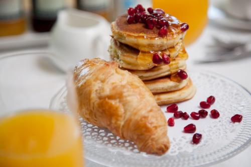 a plate with a stack of pancakes and a croissant at Serendipity Country House & Restaurant in Wilderness