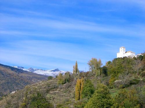 un edificio en la cima de una colina con montañas cubiertas de nieve en Casita Buena Vista, en Bubión