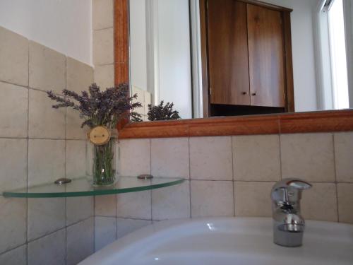 a bathroom sink with a mirror and a vase with flowers at La Cà in piaza in Cernobbio