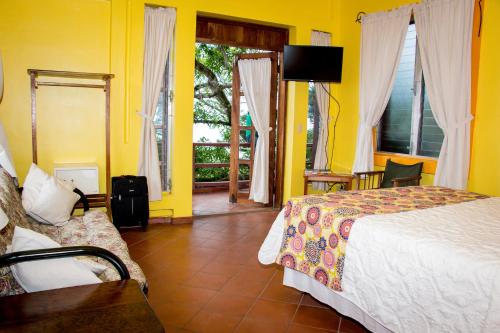 テラにあるHotel Maya Vistaのベッドルーム1室(黄色の壁、ベッド1台、ソファ付)