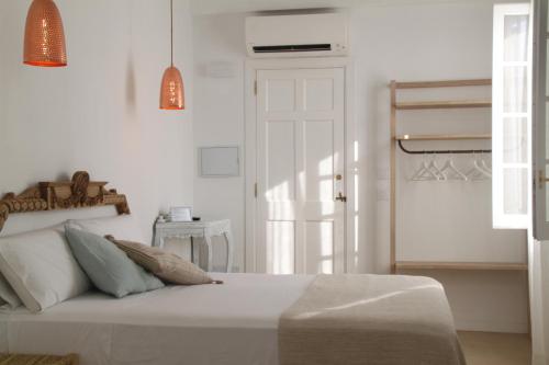 a white bedroom with a bed and a white door at S'Esparteria Hotel in Ciutadella