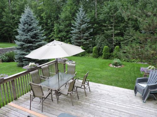 a table and chairs on a deck with an umbrella at Tucked Inn the Harbour B&B in Victoria Harbour