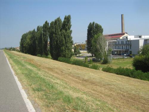 an empty field next to a building and a road at Hostiliae Ciminiera Hotel in Ostiglia