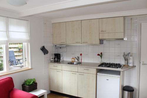 a small kitchen with wooden cabinets and a red couch at 't Hoeske in Exloo