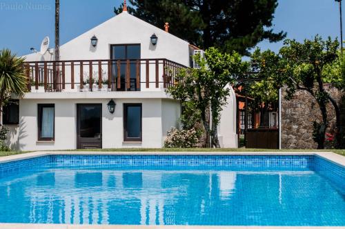 a house with a swimming pool in front of a house at Casa Da Noquinhas in Bunheiro