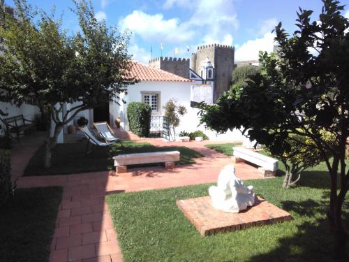 un jardin avec deux bancs et un bâtiment dans l'établissement Casa da Talhada - Stone House, à Óbidos