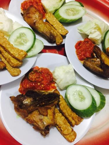 a table topped with plates of food with cucumbers and fries at Guest House Rumah Lombok Syariah in Mataram