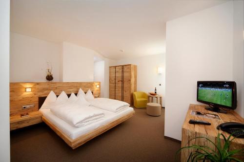 Hotel Ultnerhof في سانتا غيرترود نيليه فال دو ألتيمو: غرفة نوم بسرير ومكتب مع تلفزيون