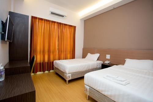 a hotel room with two beds and a television at Labuan Fortune Hotel in Labuan