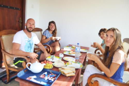 a group of people sitting around a table eating food at Woodsy Villa in Sigiriya