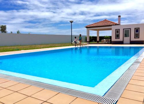 a large blue swimming pool next to a house at Casa do O in Ponta Delgada