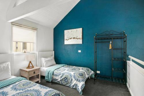 a bedroom with two beds and a blue wall at Terrace Lofts Apartments in Ocean Grove