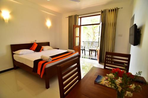 a bedroom with a bed and a table and a window at Park Lane Apartments in Negombo