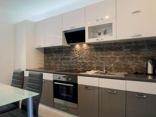 a kitchen with white cabinets and a sink and a table at DELUXE Rožnov in Rožnov pod Radhoštěm