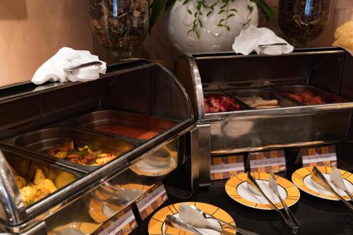 a buffet with two trays of food and plates of food at Norfolk Mansion - Luxury Serviced Apartment in Ho Chi Minh City