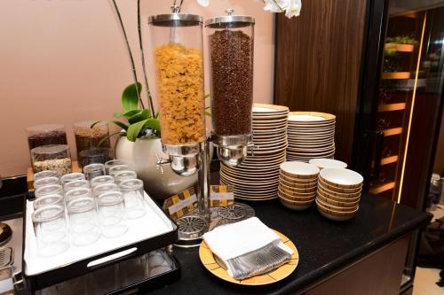 a counter with two vases filled with food and stacks of plates at Norfolk Mansion - Luxury Serviced Apartment in Ho Chi Minh City