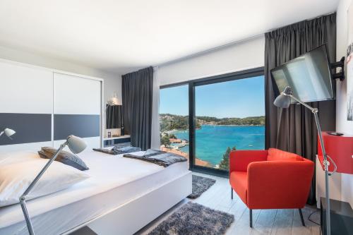 a bedroom with a bed and a red chair and a large window at Residence Alpha Apartments in Cavtat