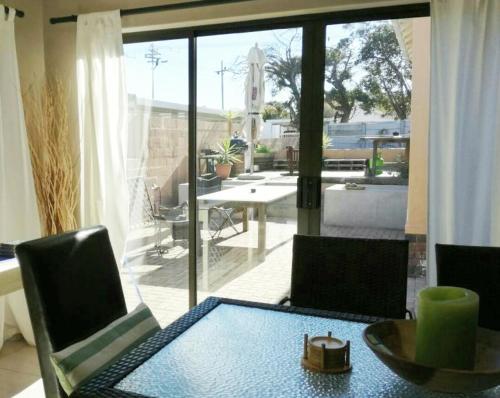 a living room with a table and chairs and a patio at Milnerton Guesthouse in Cape Town