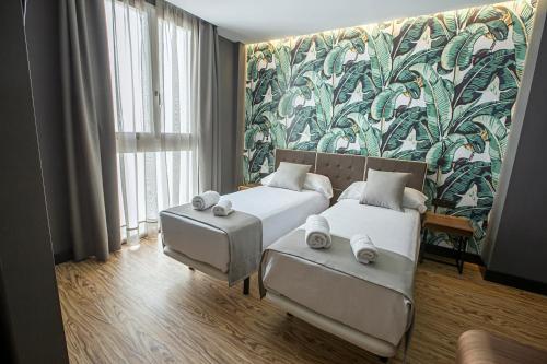 a bedroom with two beds and a couch and a mural at Málaga Premium Hotel in Málaga