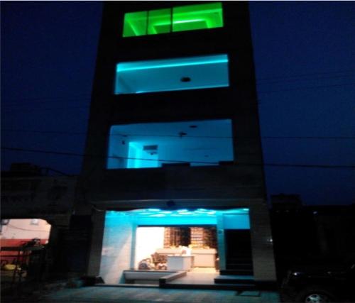 un edificio alto con una señal verde encima en Hotel Gill Tower, en Hanumāngarh