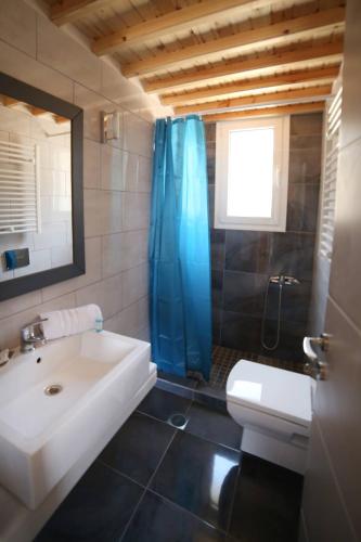 a bathroom with a sink and a blue shower curtain at Blue SeaSide Studios in Fanari