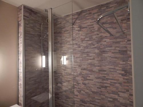 La salle de bains est pourvue d'une douche et d'un mur en briques. dans l'établissement T3 Les Peupliers proche Pasino et mer, à La Grande Motte