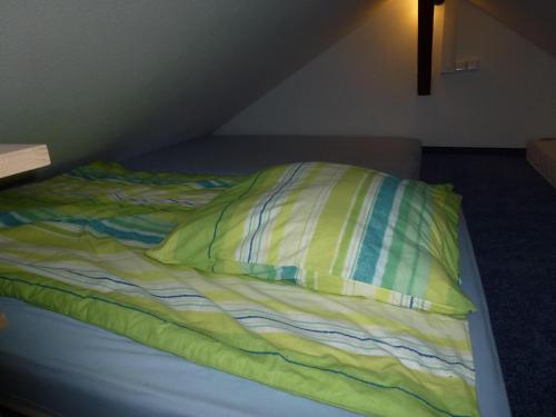a unmade bed with a yellow pillow on it at Ferienhaus im Nordschwarzwald in Pforzheim