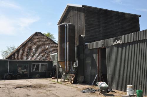 a black building with a water tank next to a house at Sitting at the Bay in Zuiderwoude