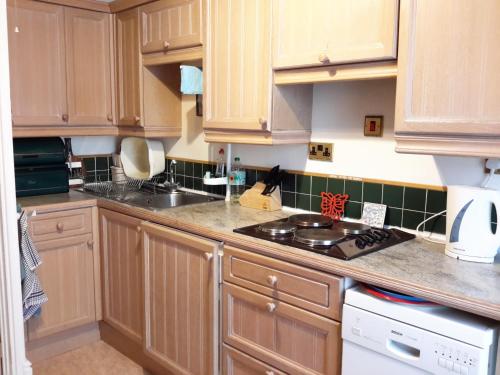 a kitchen with wooden cabinets and a stove top oven at Lupine Cottage in Whitby