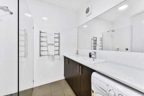 a white bathroom with a sink and a shower at Robe Marina Accommodation in Robe