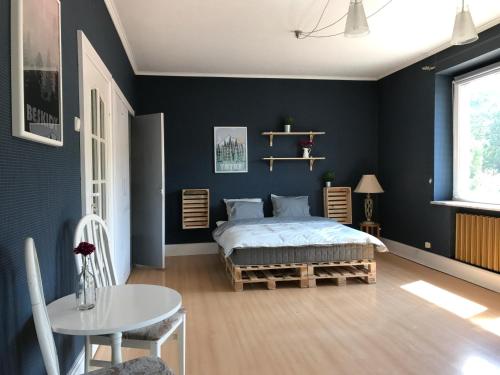 ヴィスワにあるApartament Przy Rynkuの青い壁のベッドルーム1室、ベッド1台、テーブルが備わります。