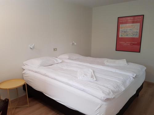 ein weißes Bett mit weißer Bettwäsche und Handtüchern darauf in der Unterkunft Fermata North in Laugar