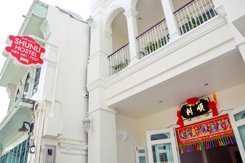 a white building with a sign in front of it at Shunli Hotel - SHA Extra Plus in Phuket Town