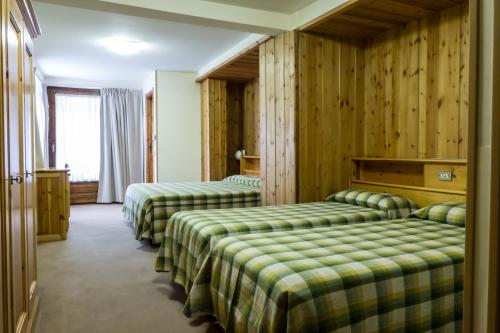 dwa łóżka w pokoju z drewnianymi ścianami w obiekcie Hotel Valdotain w mieście Villeneuve
