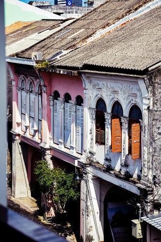 an old building with white and orange shuttered windows at Shunli Hotel - SHA Extra Plus in Phuket Town