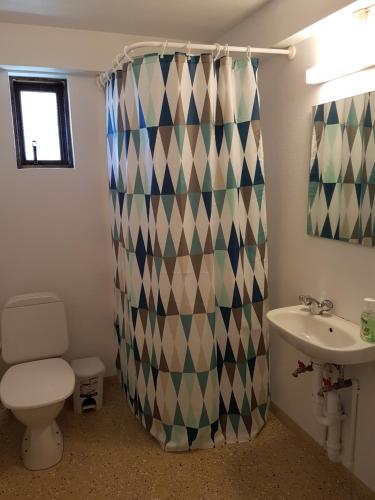 a bathroom with a toilet a sink and a shower curtain at Fermata North in Laugar