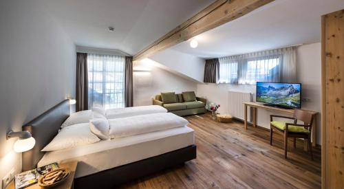 a bedroom with a large bed and a living room at Hotel Spanglwirt in Campo Tures