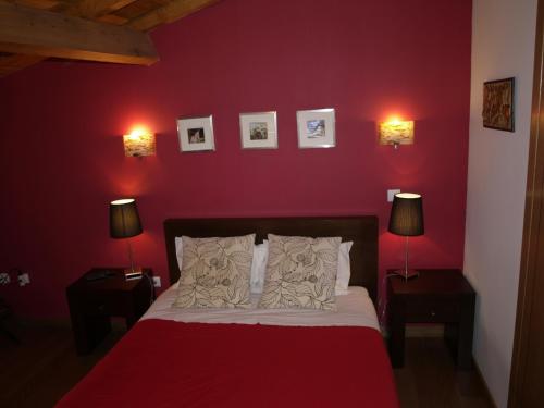 a bedroom with a red wall with a bed and two lamps at Casa Princesa Peralta in Lousã