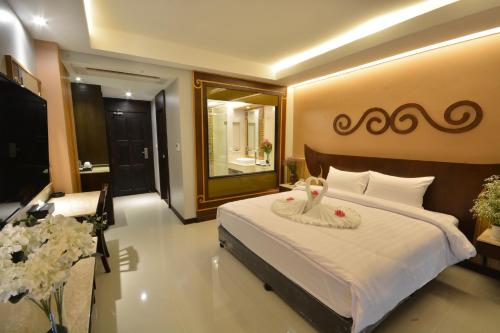 a bedroom with a large white bed and a mirror at Le Bali Resort in North Pattaya