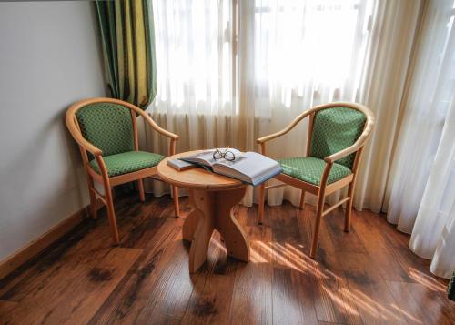 a room with two chairs and a table with a book at Hotel Alpi in Campitello di Fassa